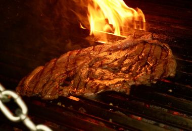 Carne asándose a la parrilla con fuego vivo en El Fogón del Che Oceanía